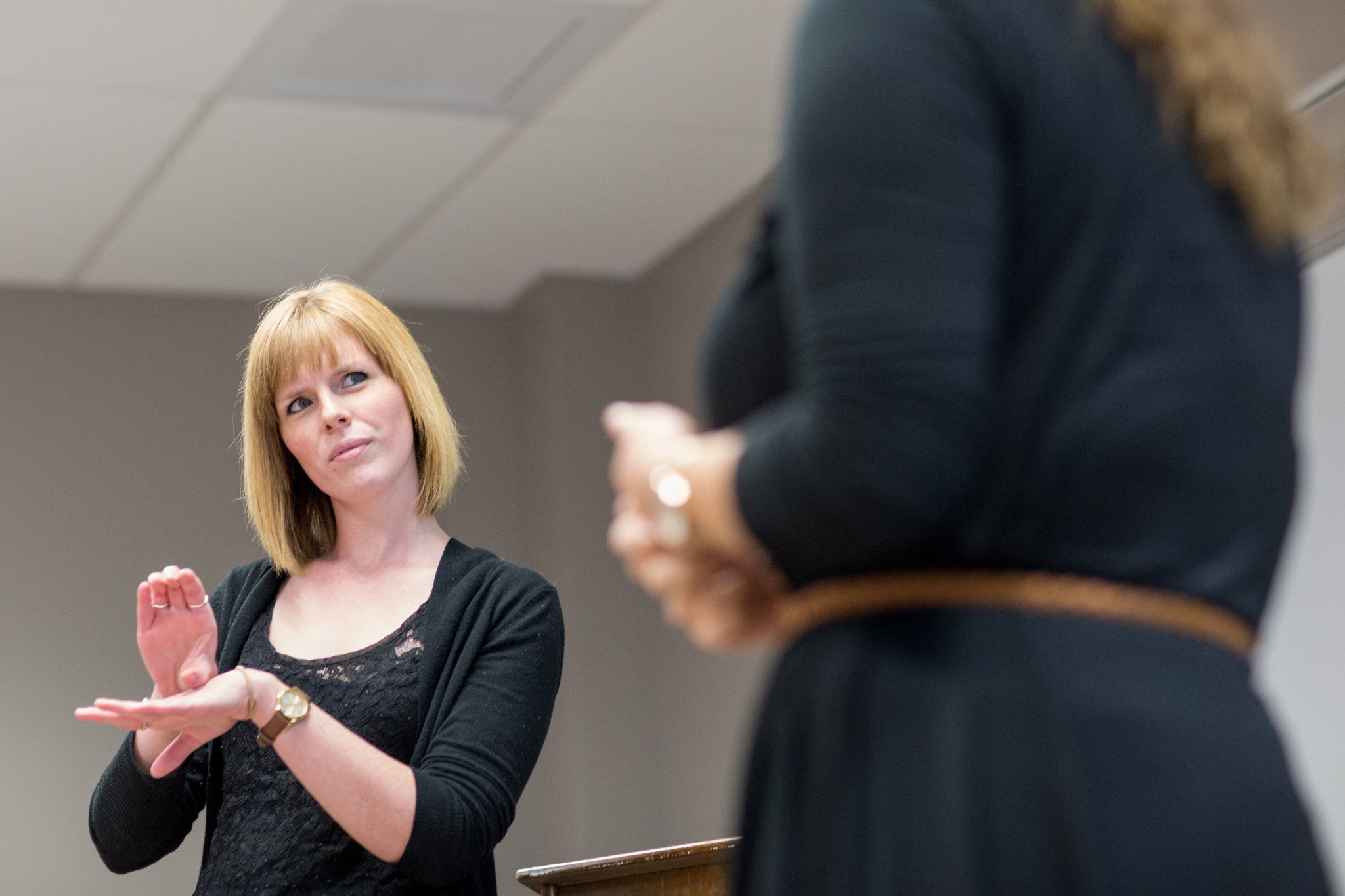 A woman with blond hair demonstrates sign language