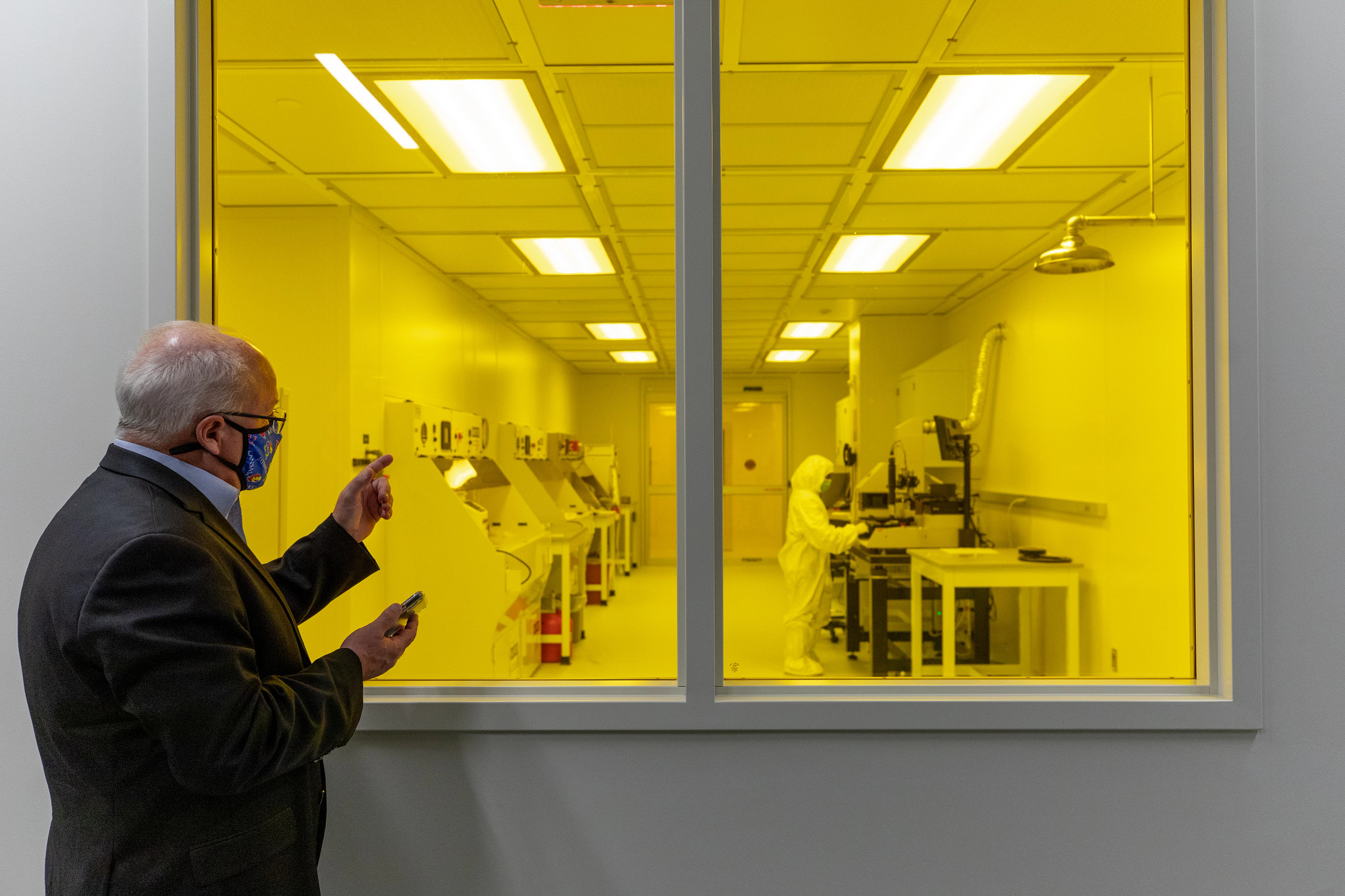 man in sport coat standing in front of lab bathed in yellow light