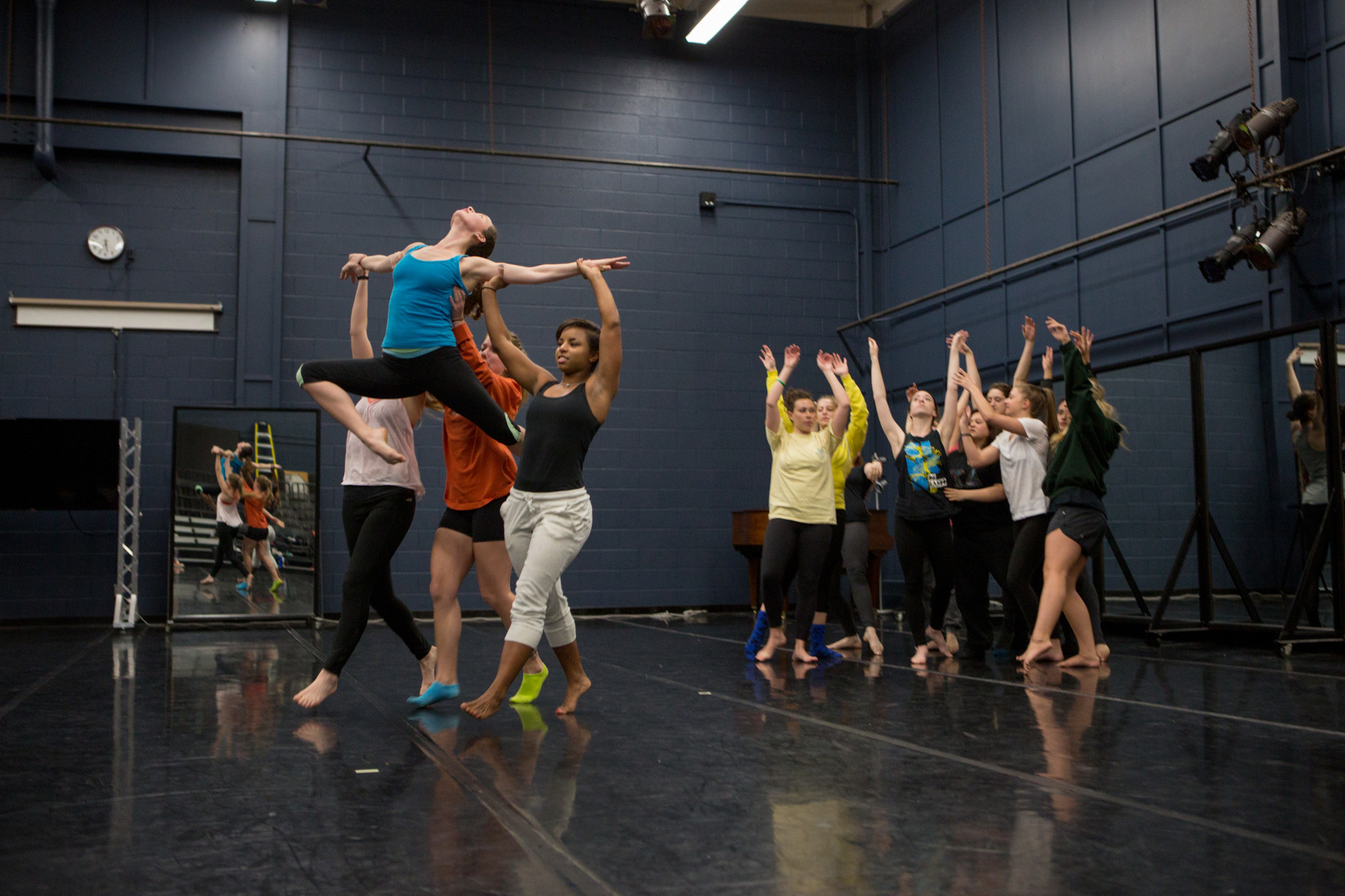 Dancers lift one dancer as they make their way across a stage