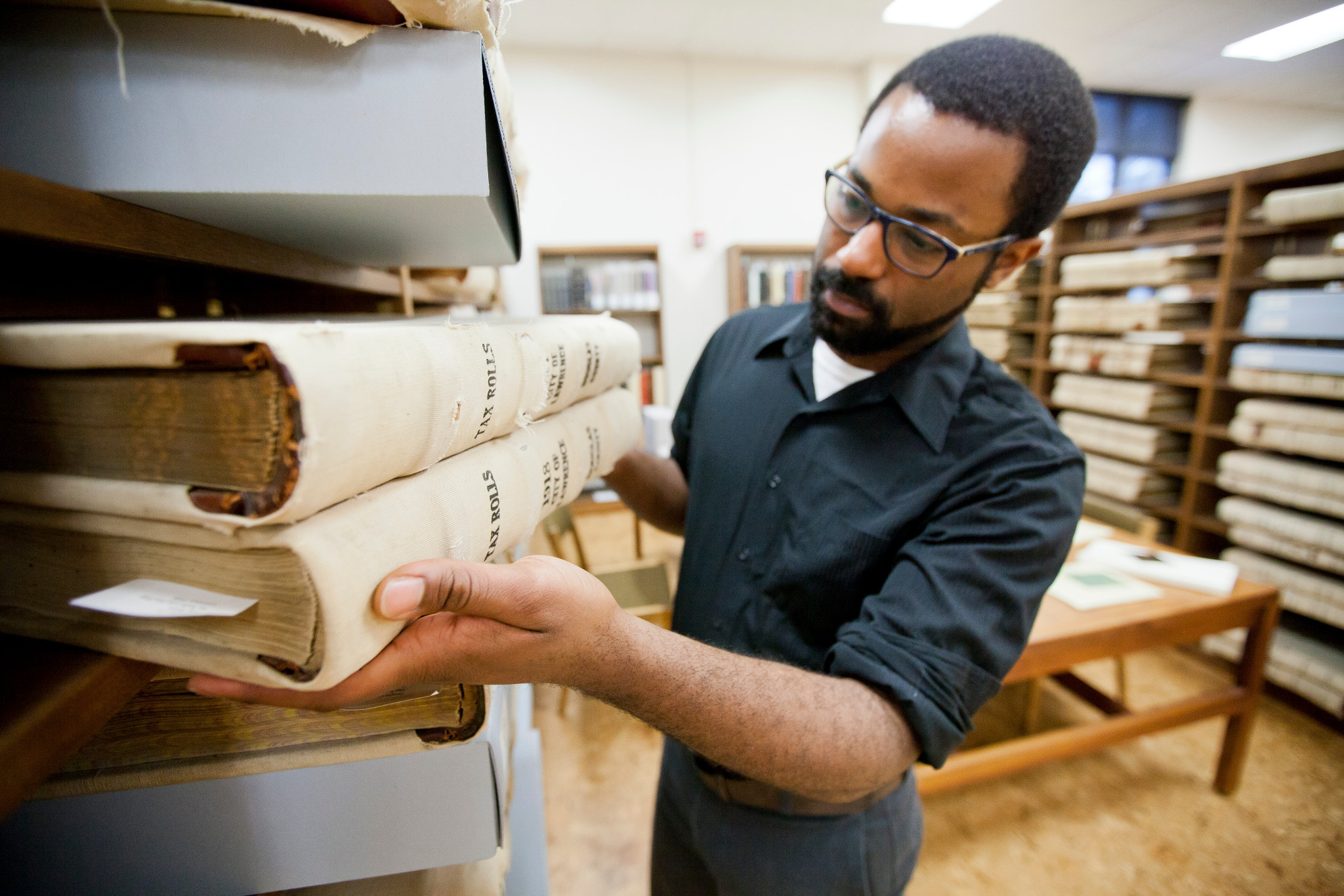 student places ancient texts on a shelf in spencer research library