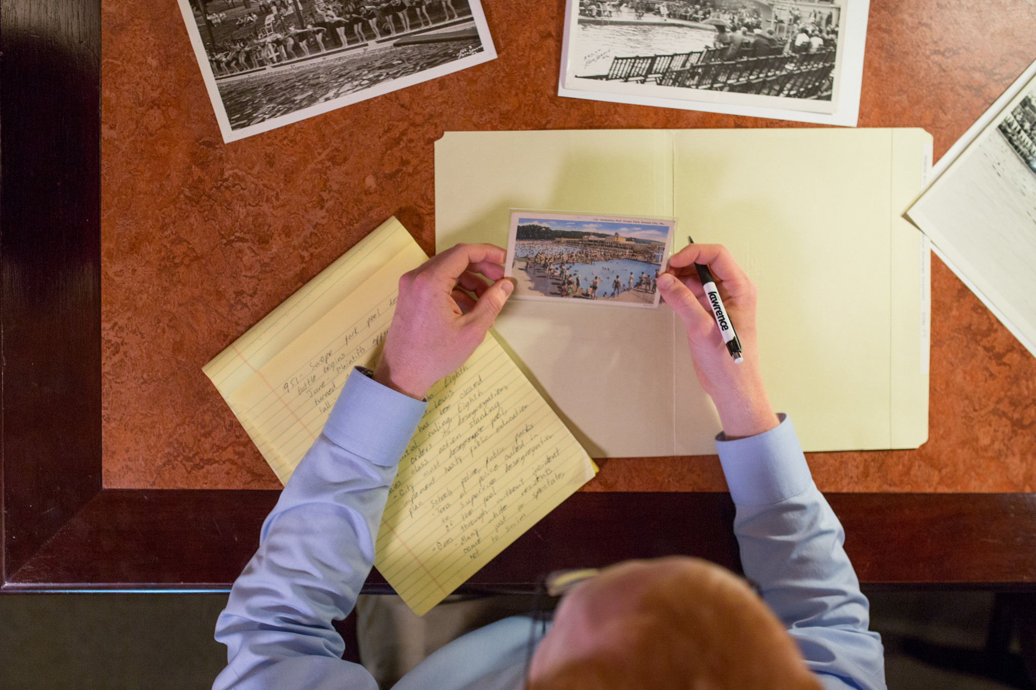 top down view of student in blue shirt with red hair who is looking at black and white photo white photo