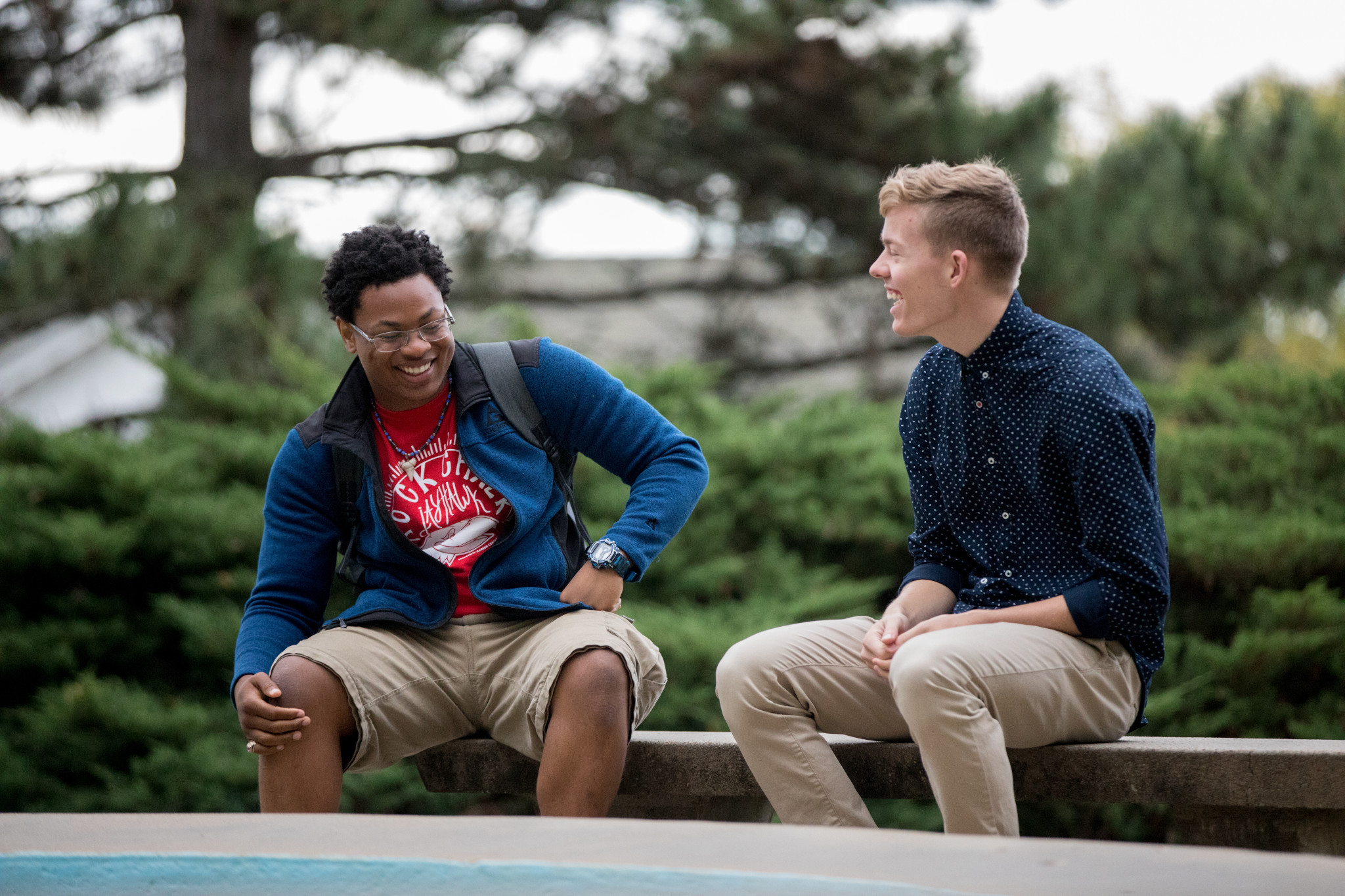 two students laughing on a bench